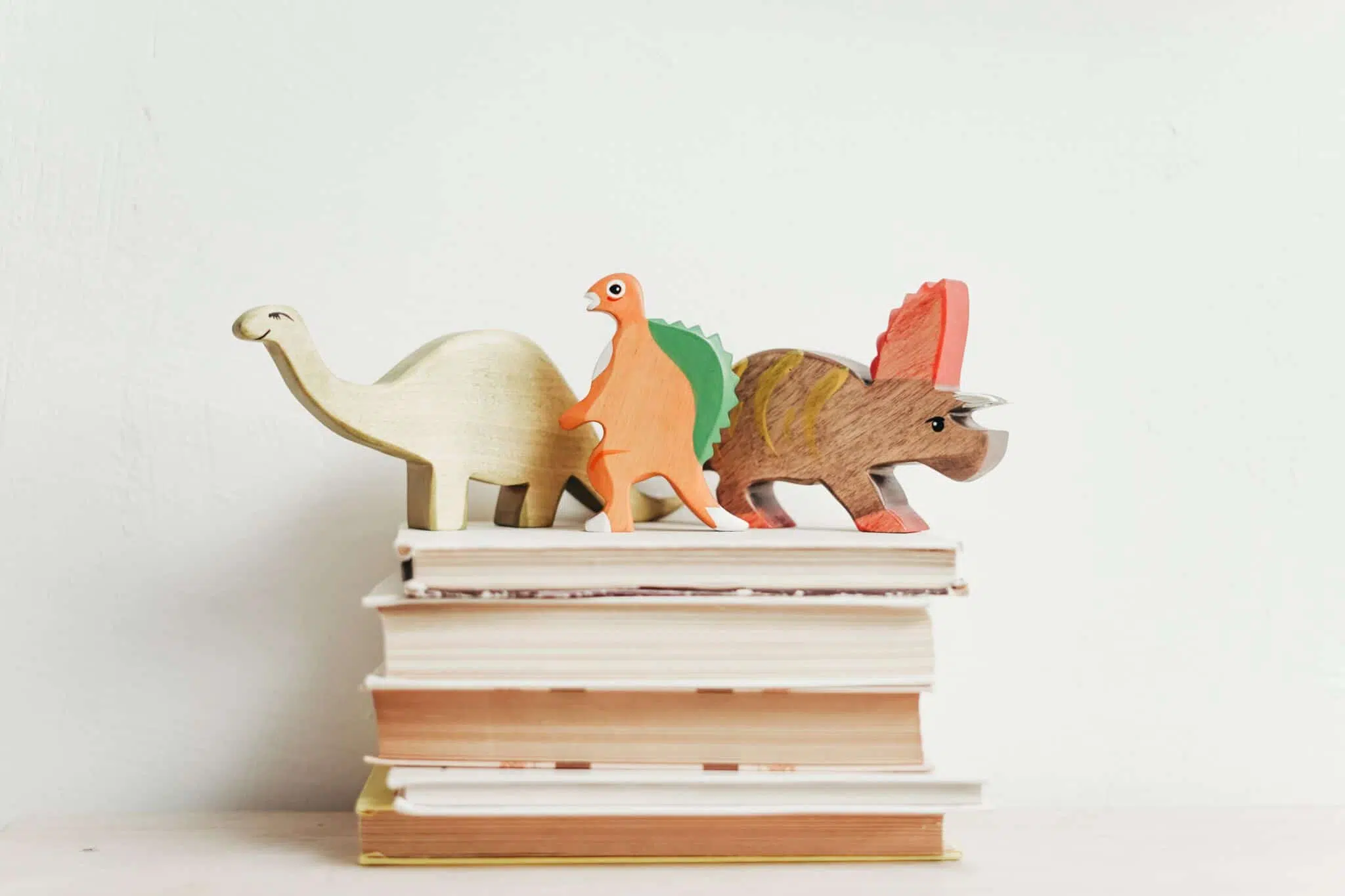 Dinosaurier-Figuren auf einem Stapel Bücher; Spielend Lesen lernen Unterstützung für Kinder